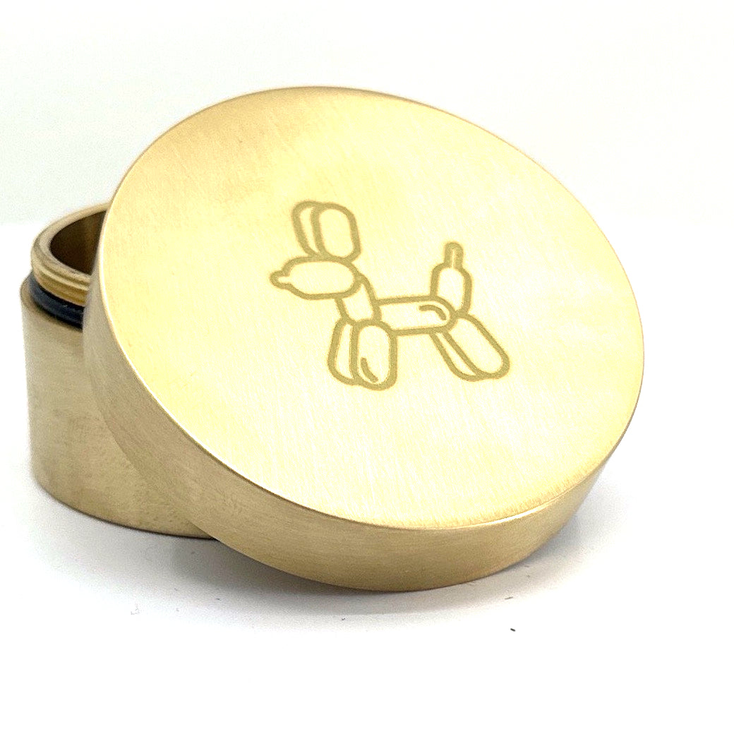 A brass weed grinder with a puffy puppy logo.