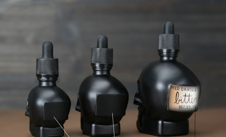 Three black skull dropper on a table.